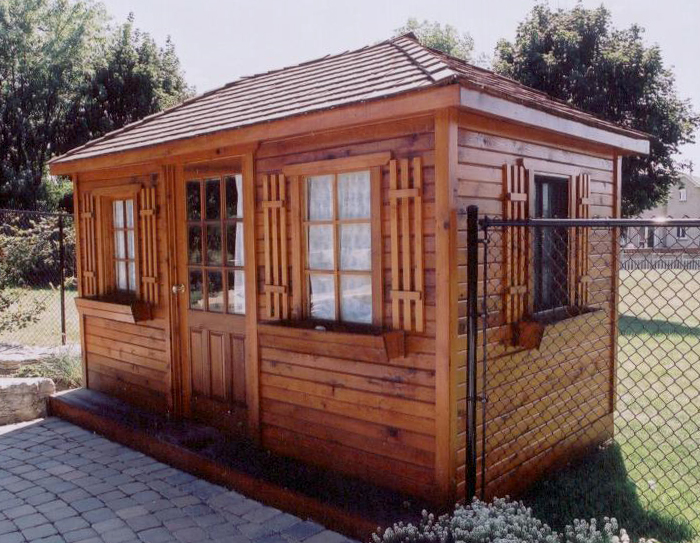 Long cedar shed with shutters on a paved patio